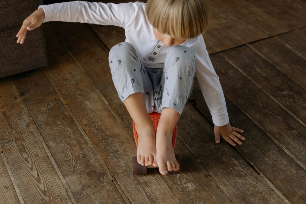 Young boy balancing on a penny board indoors, capturing playful and fun moments.