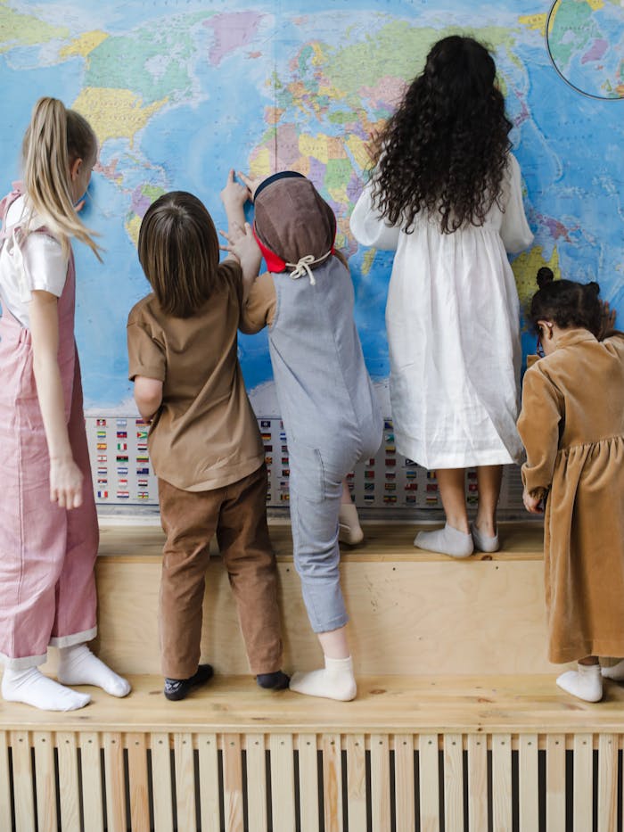 gallery-3 Five children studying a world map indoors, fostering curiosity and learning.