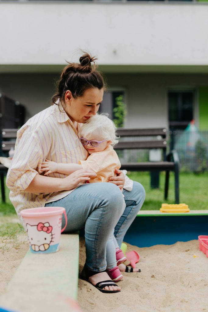 A loving mother embraces her daughter in a sandbox, showcasing tender family moments.
