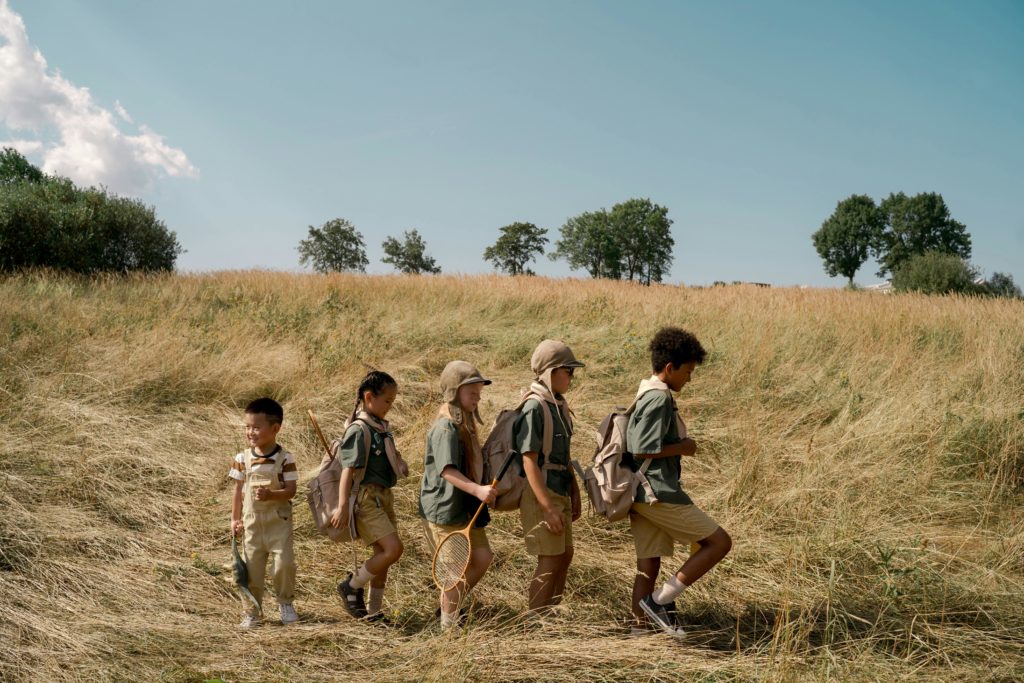 pexels photo 9290038 9290038 Group of kids exploring a sunny field on an outdoor adventure at summer camp.